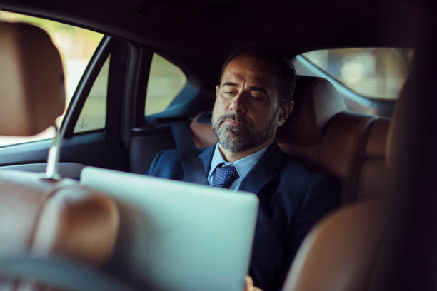 close up of a businessman in the backseat using a laptop